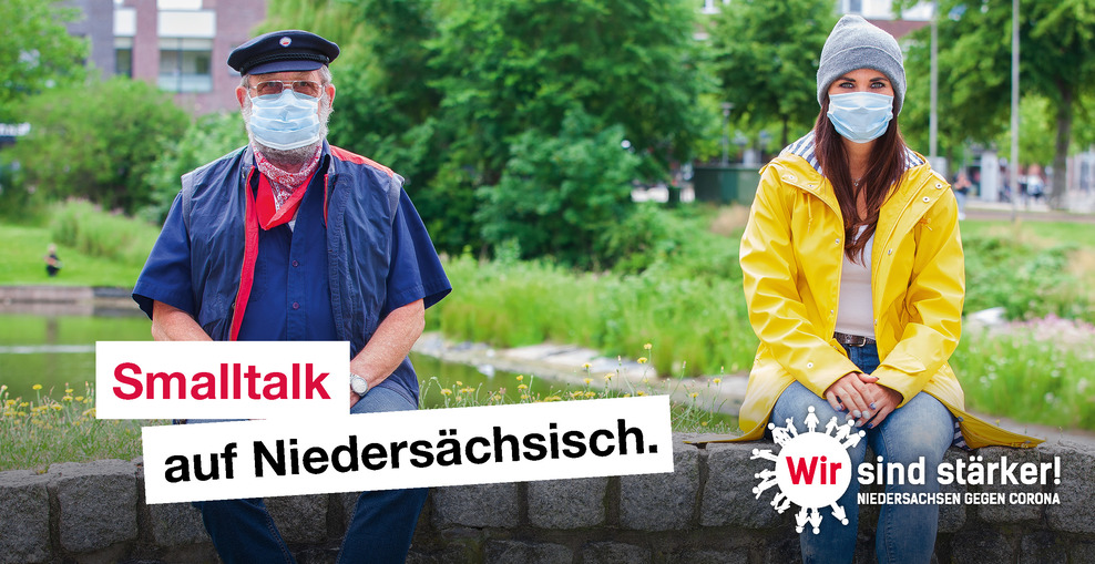 "Smalltalk auf Niedersächsisch: Ein älterer Mann und eine junge Frau sitzen mit Mundschutz auf einer Mauer und unterhalten sich (Verlinkung zu www.niedersachsen.de und Niedersachsen gegen Corona)"